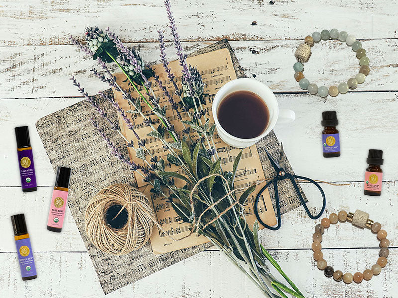 silk road organic roll-ons, euro bottles and diffusers lay flat on a table surrounding a bunch of lavender and twine next to a coffee cup