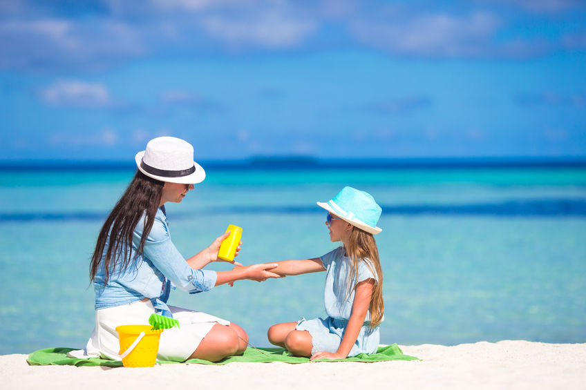 on the beach, woman applying sunscreen to a young child