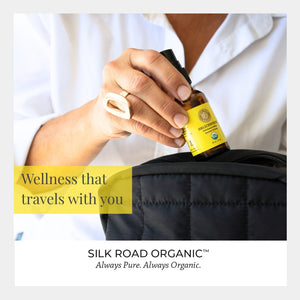 Person holding a bottle of Silk Road Organic product with text 'Wellness that travels with you' and brand name.