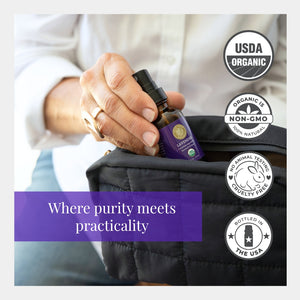 Hand holding a bottle of lavender essential oil with USDA Organic, Non-GMO, Cruelty-Free, and USA-bottled labels.