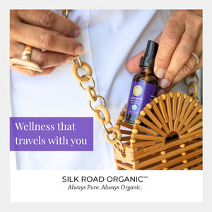 Bottle of Silk Road Organic product held by a hand with a wooden bag in the background
