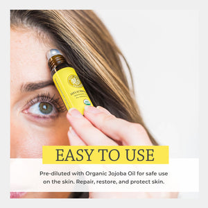 Person applying a yellow bottle of organic helichrysum blended jojoba oil to their face with text about its use. easy safe applications topical directly skin diluted golden jojoba repair restore protect