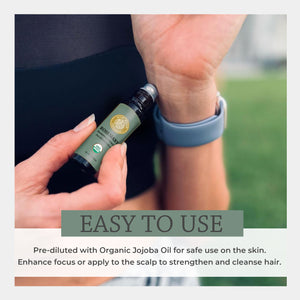 Hand holding a bottle of organic rosemary jojoba oil with text about its use. easy safe cleansing apply scalp massage dandruff relief wash stimulating fresh scent energize